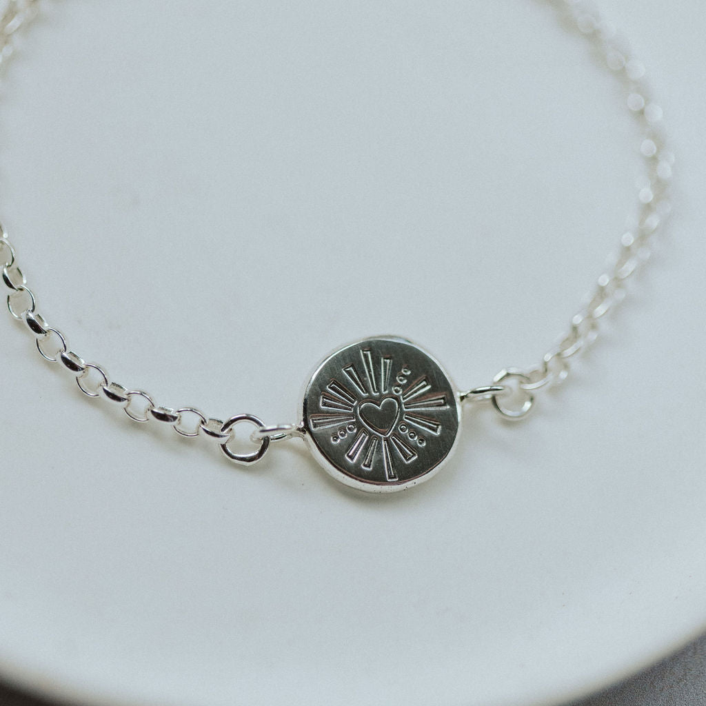 Silver bracelet with a heart design on a white plate