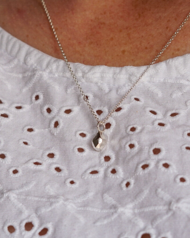 Silver geometric pendant on silver chain, shown on a model.