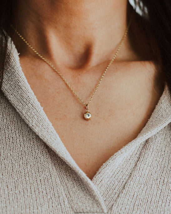 Lady wearing gold pebble pendant set with birthstone.