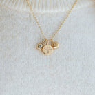 Gold necklace with phoenix, birthstone and initial pendants on a white sweater