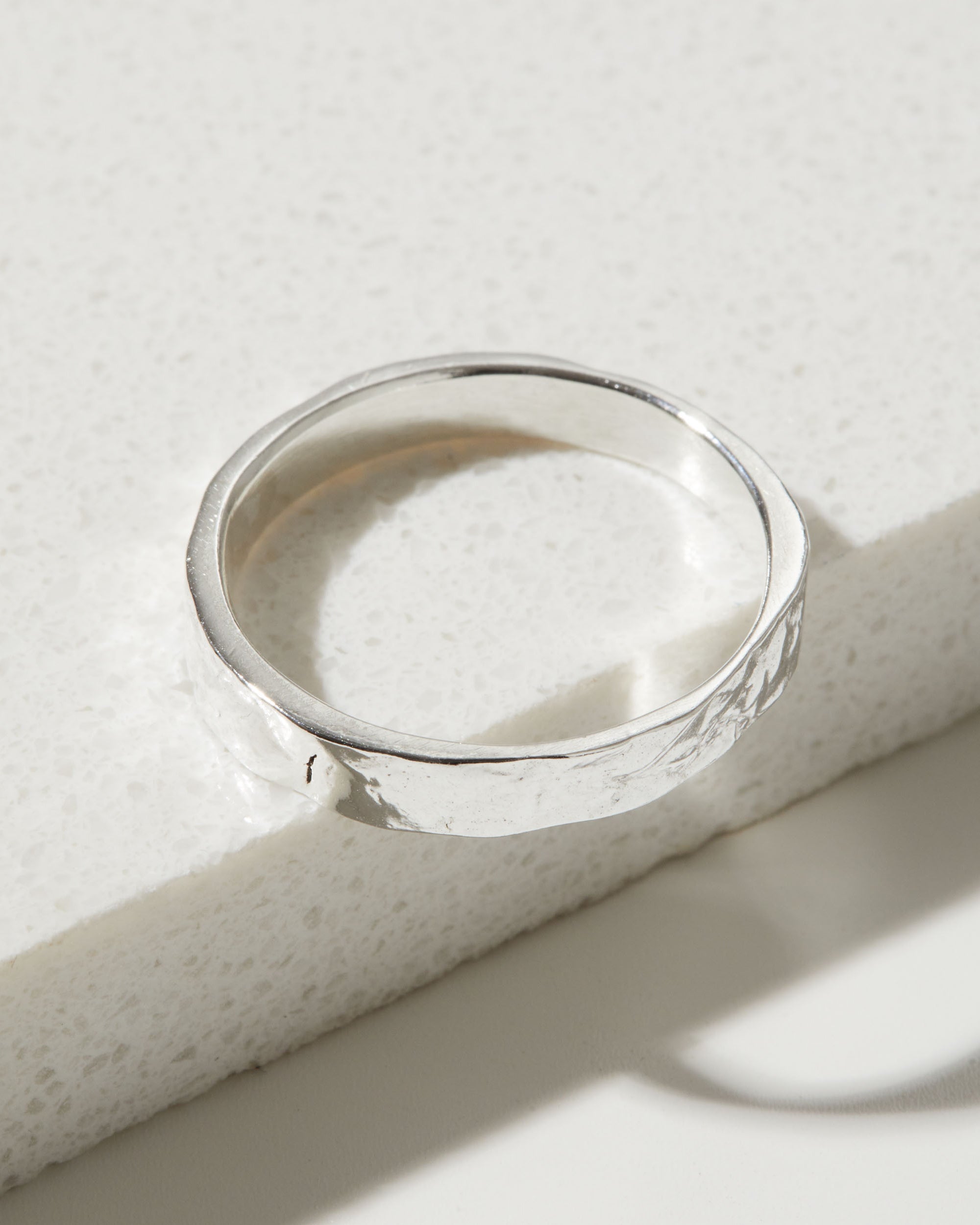 Silver bark textured ring on a textured white surface