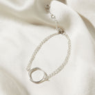 Silver bracelet with a circular design on a soft beige fabric background