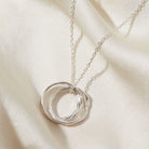 Silver necklace with a double circular pendant on a beige fabric background