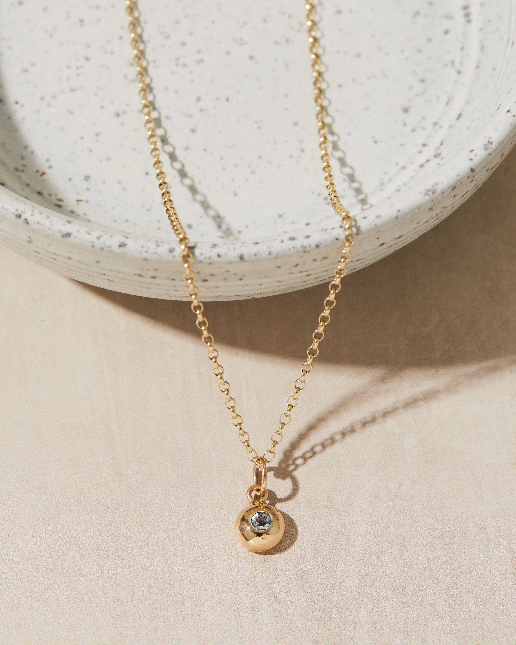 Gold necklace with a birthstone pendant on a neutral background