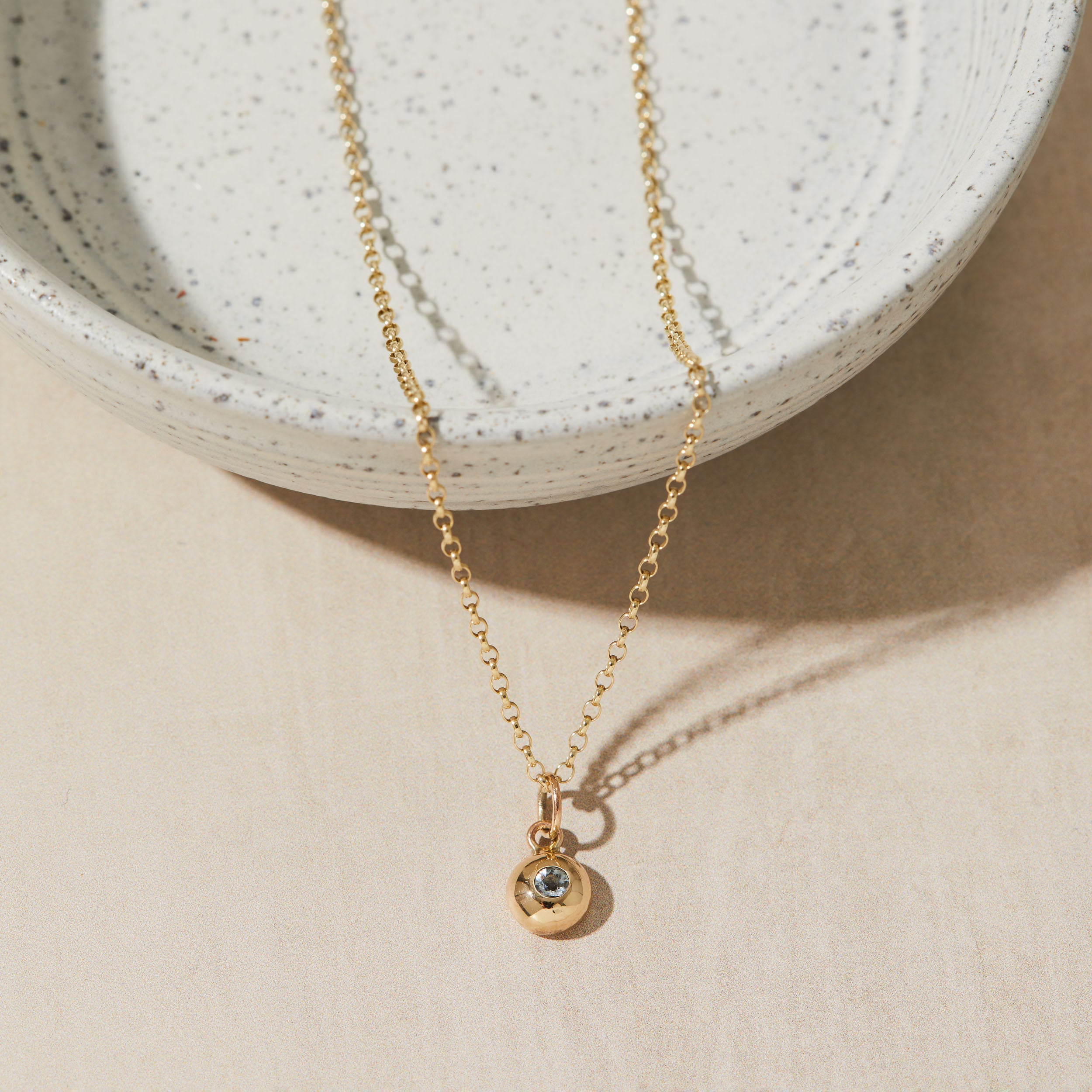 Gold necklace with a birthstone pendant on a neutral background