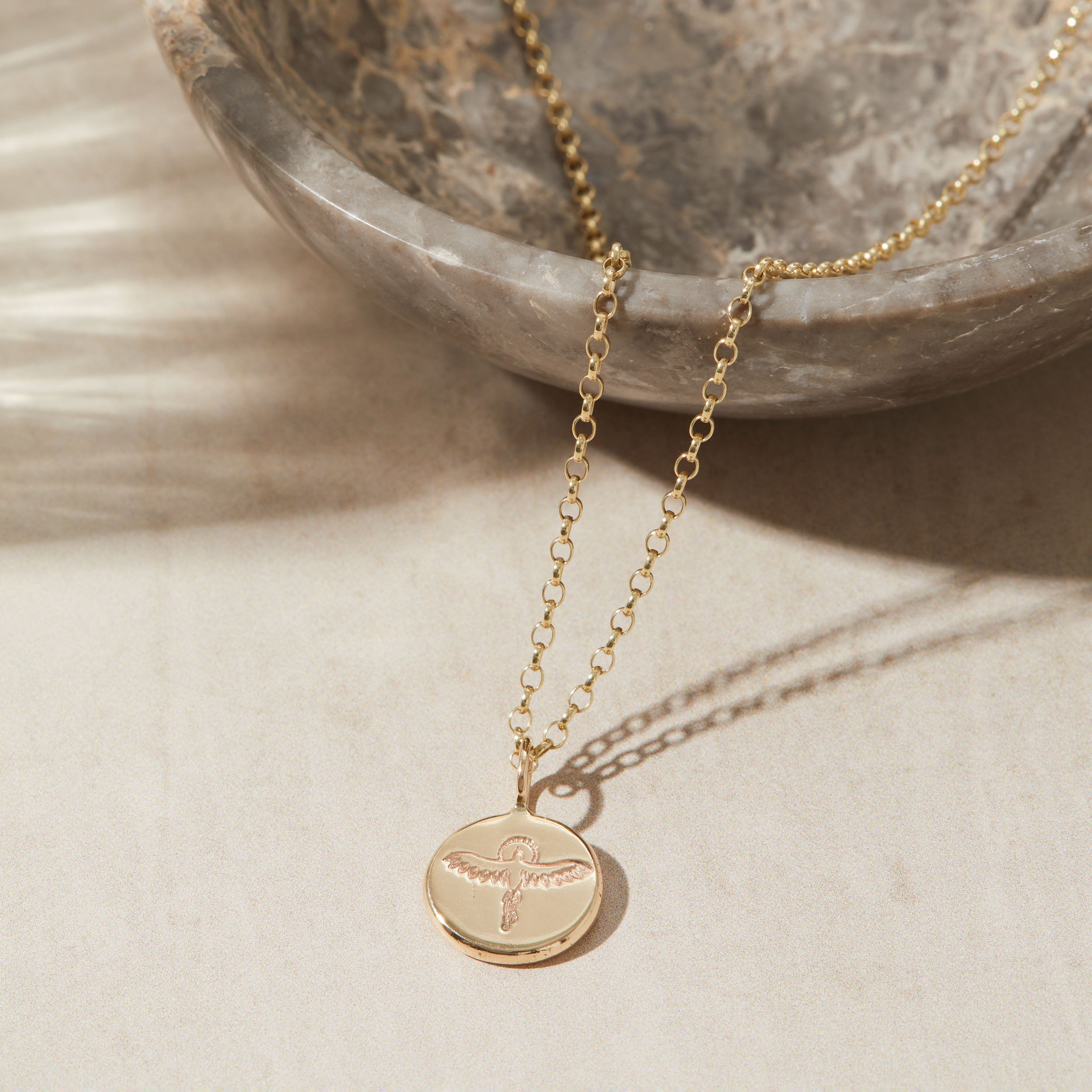 Gold necklace with a pendant on a neutral background