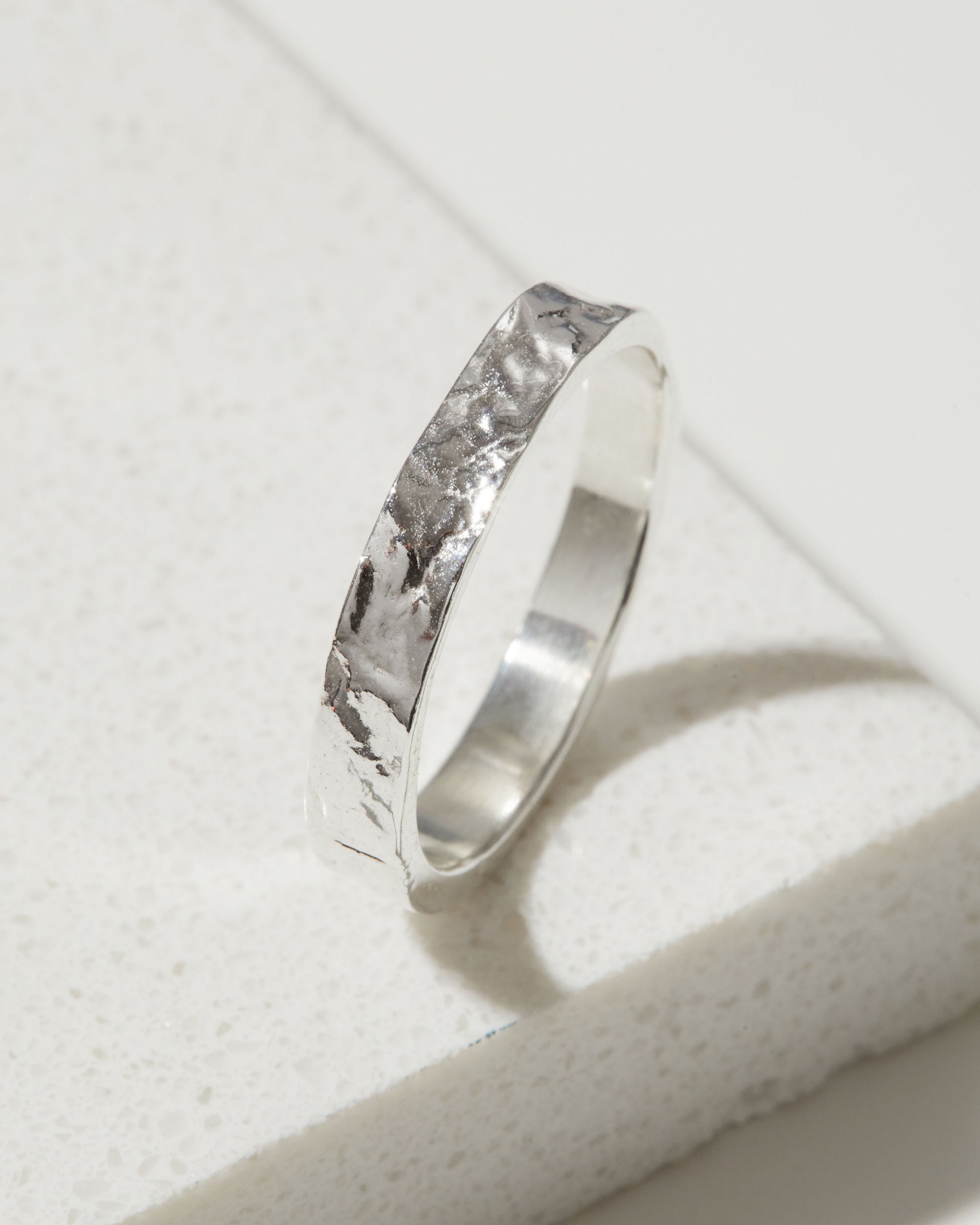 Silver ring with a bark textured band on a light gray background