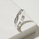 Silver ring with a bark textured band on a light gray background
