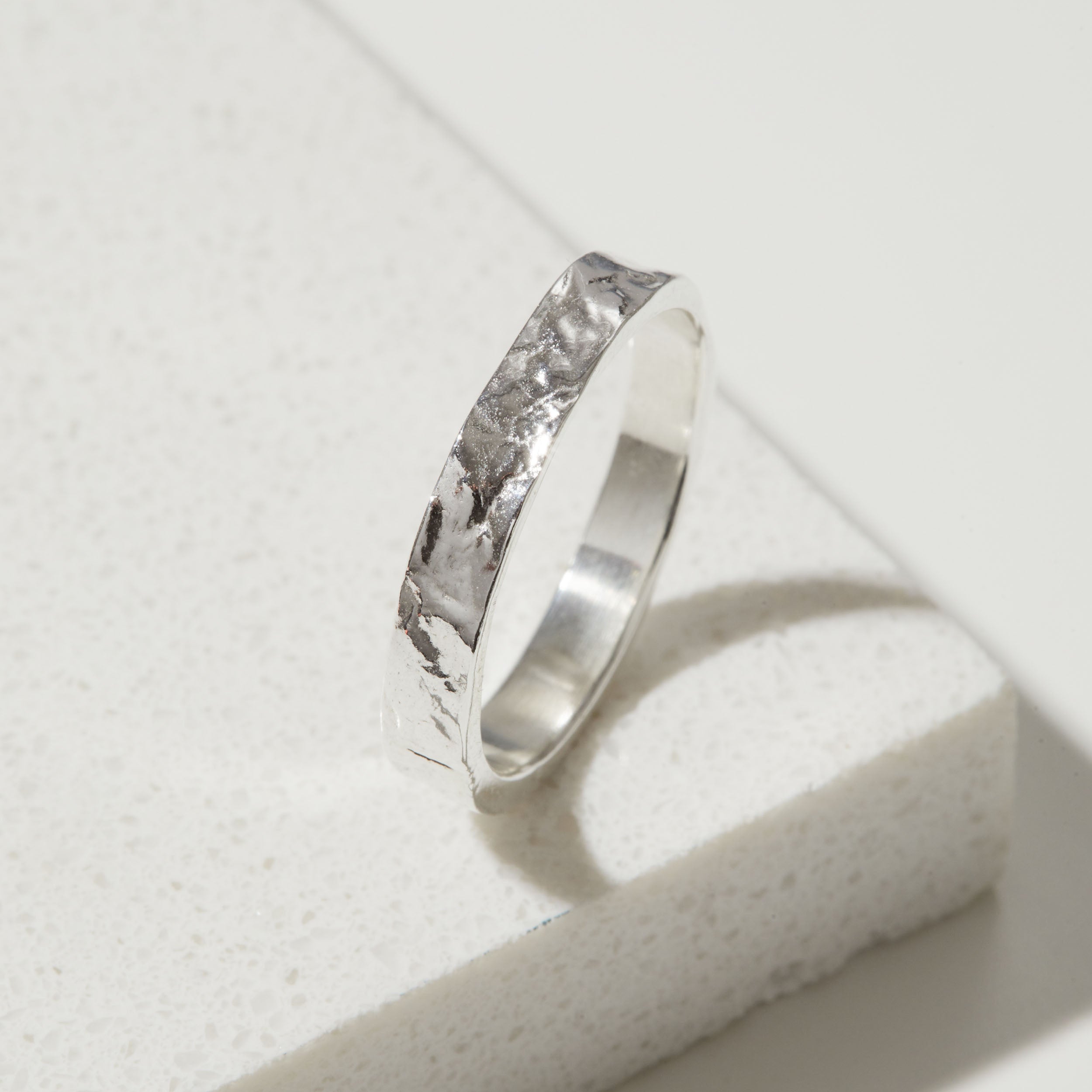 Silver ring with a bark textured band on a light gray background