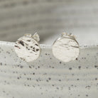 Silver round bark textured stud earrings on a speckled gray surface