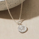 Silver necklace with a heart pendant on a beige surface