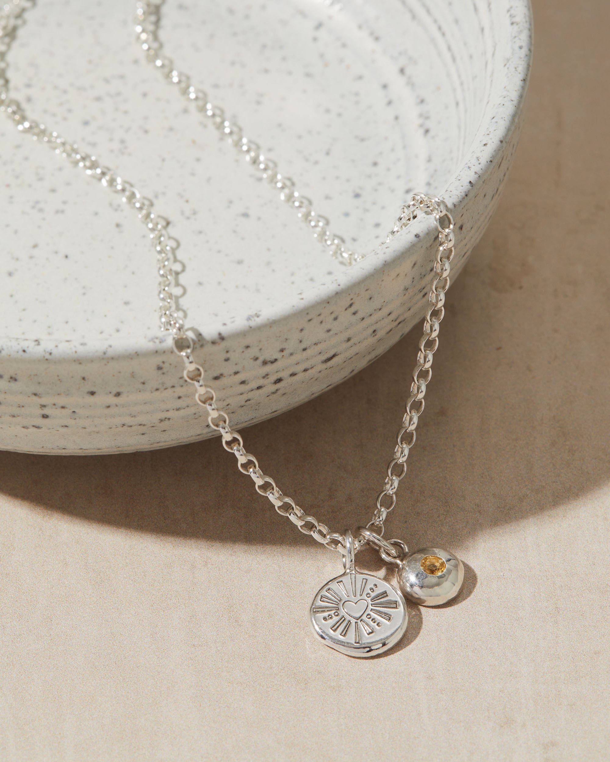 Silver necklace with two pendants on a textured surface