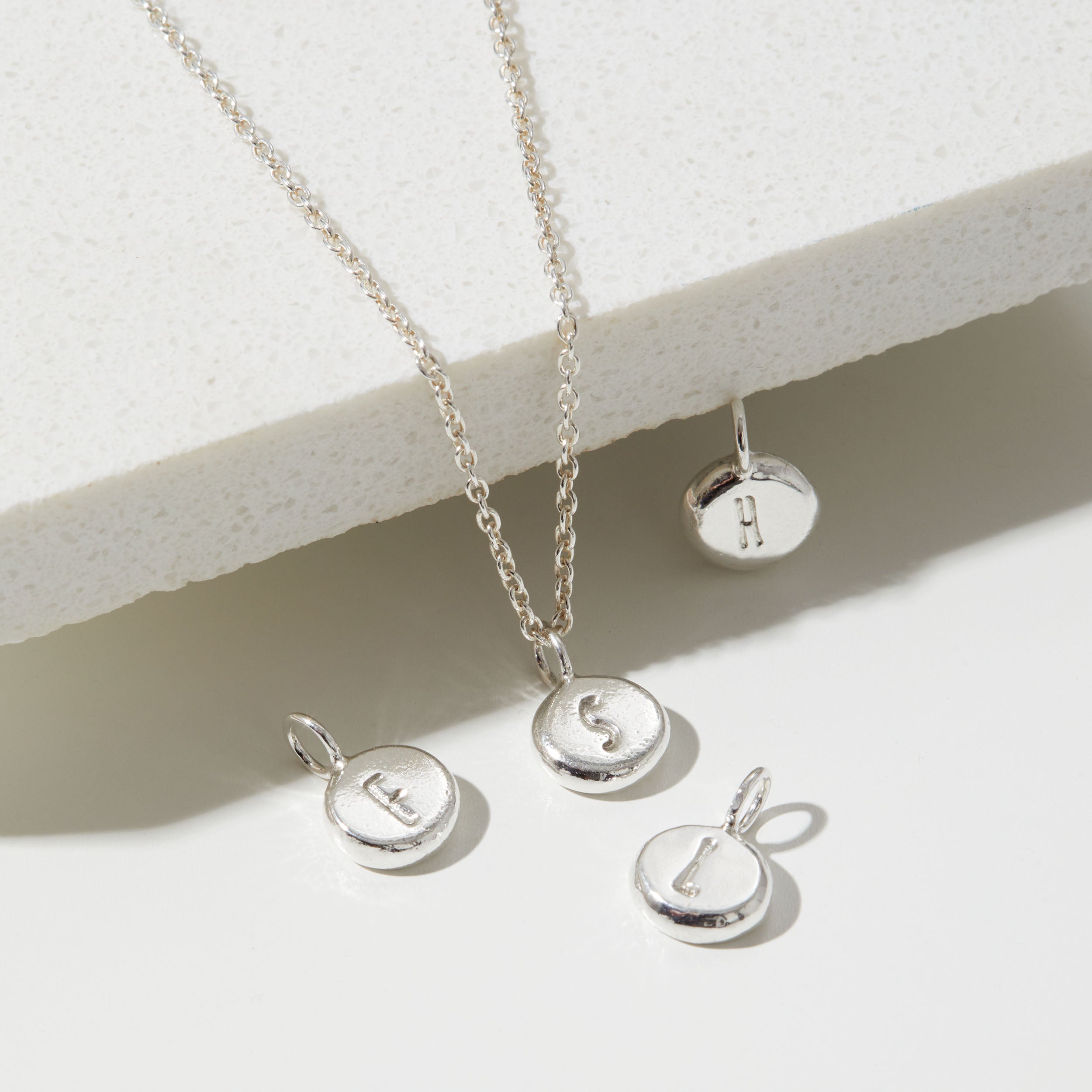 Silver necklace with round pendants on a light background
