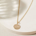 Gold necklace with a phoenix pendant on a light beige background