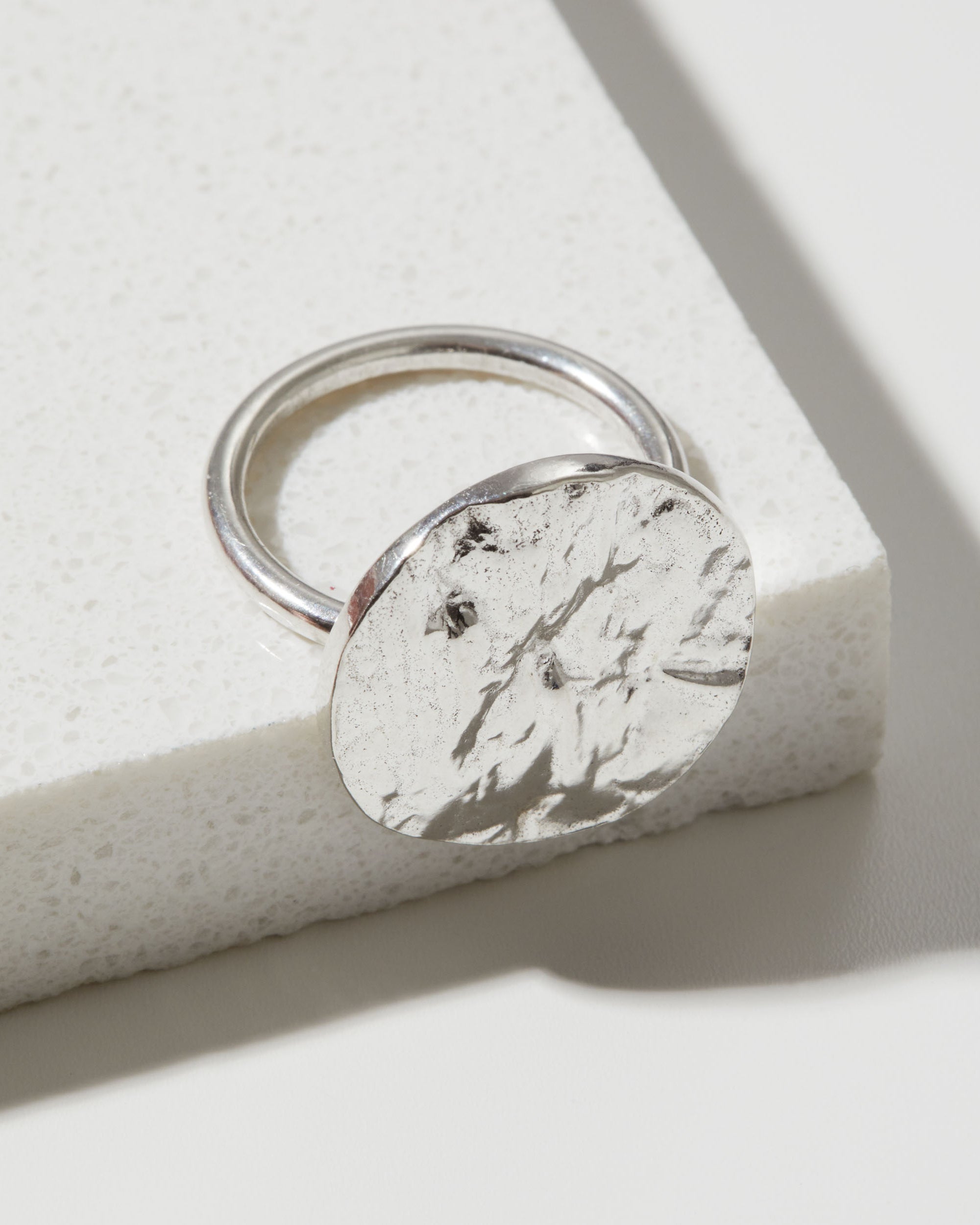 Silver ring with a bark textured circular design on a light background
