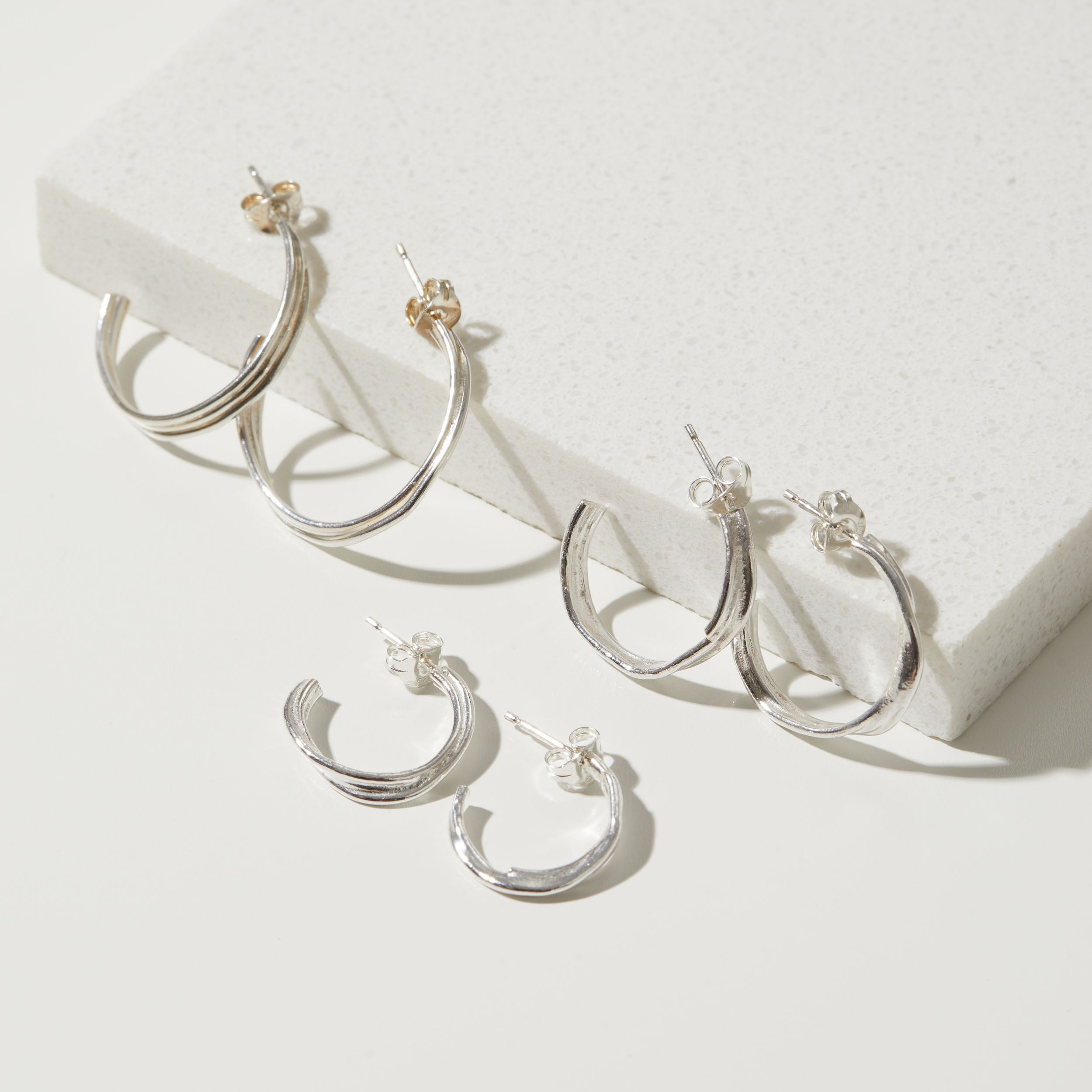 Set of silver hoop earrings on a white surface