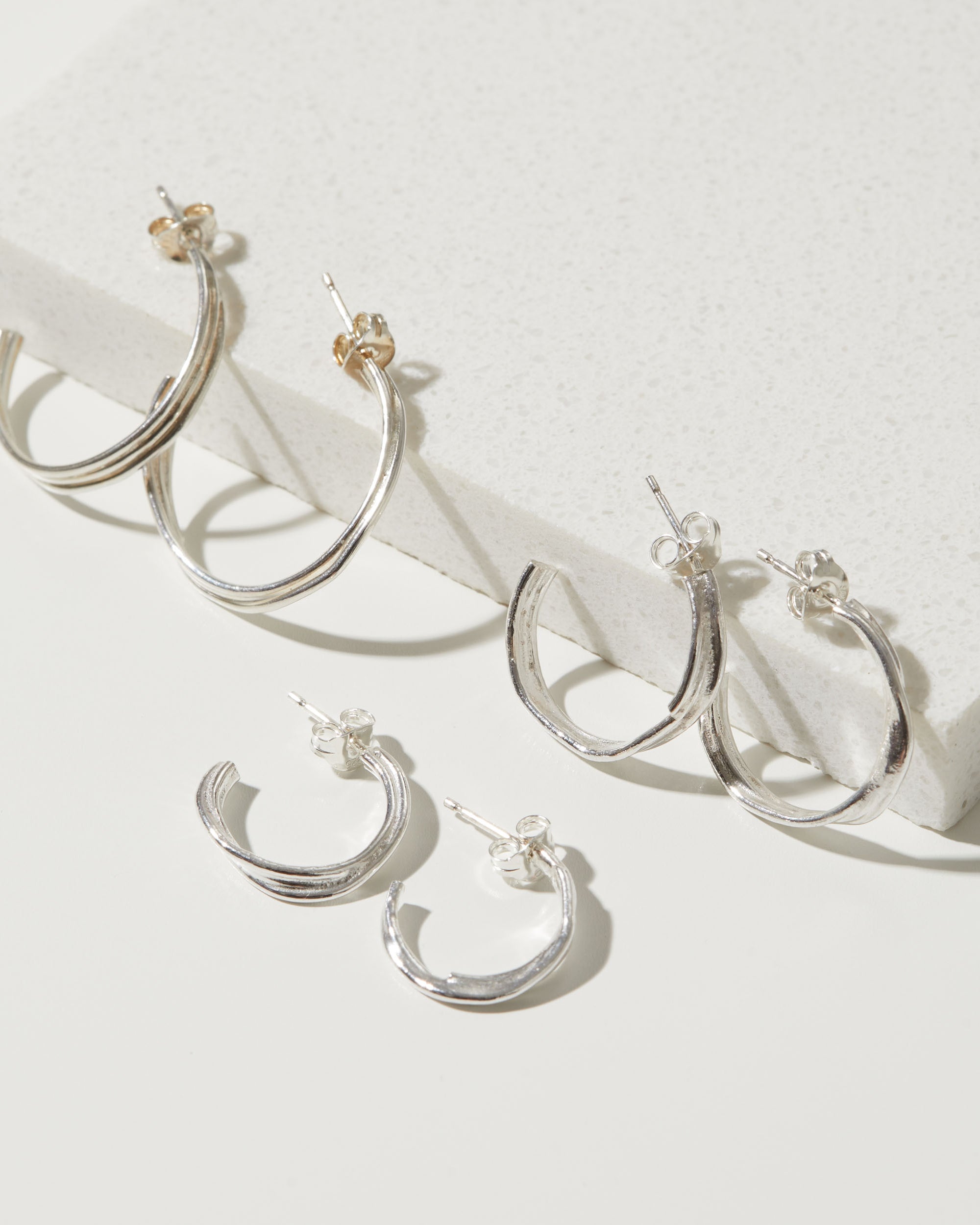 Set of silver hoop earrings on a white surface