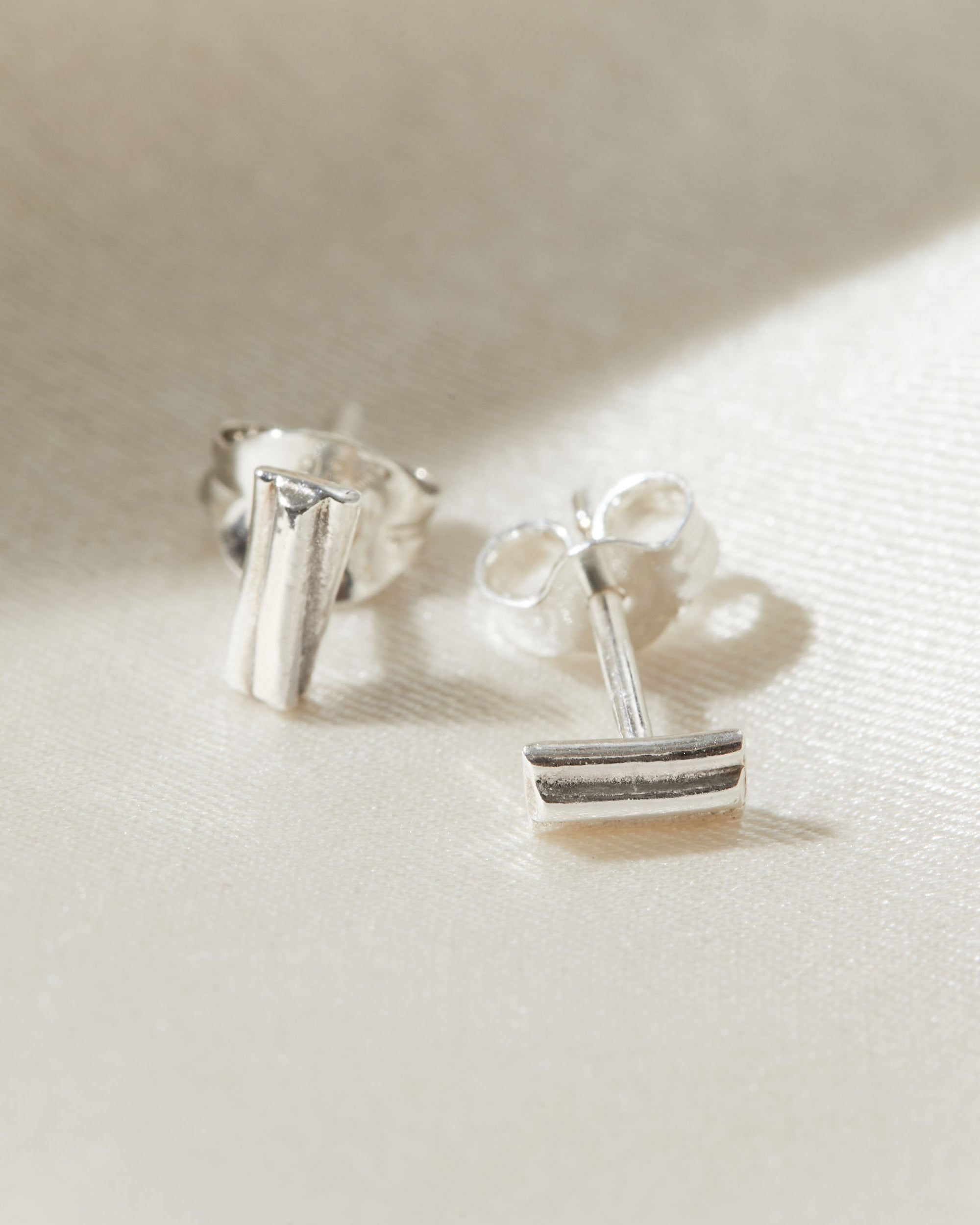 Silver stud earrings on a light fabric background