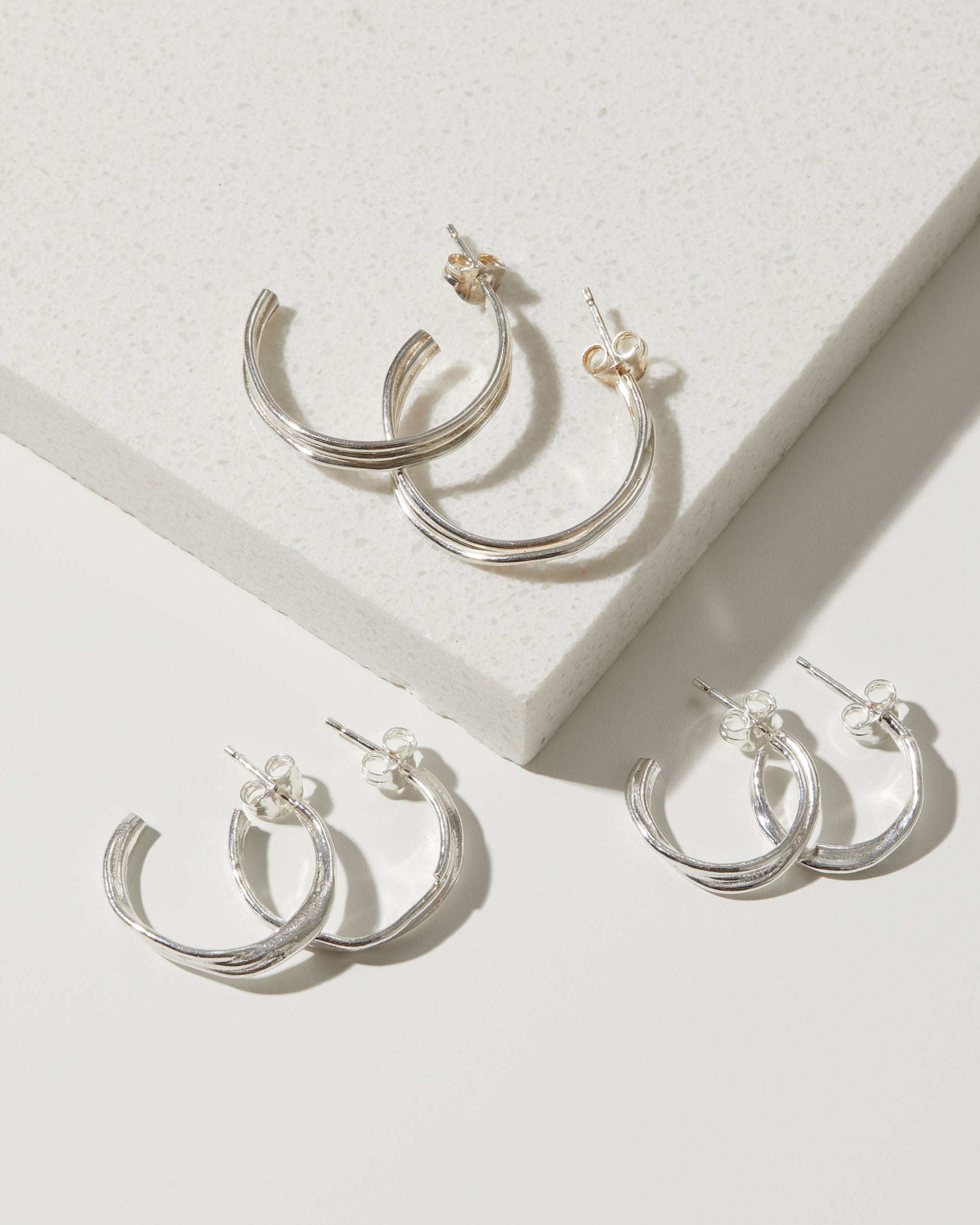 Silver hoop earrings on a light gray surface