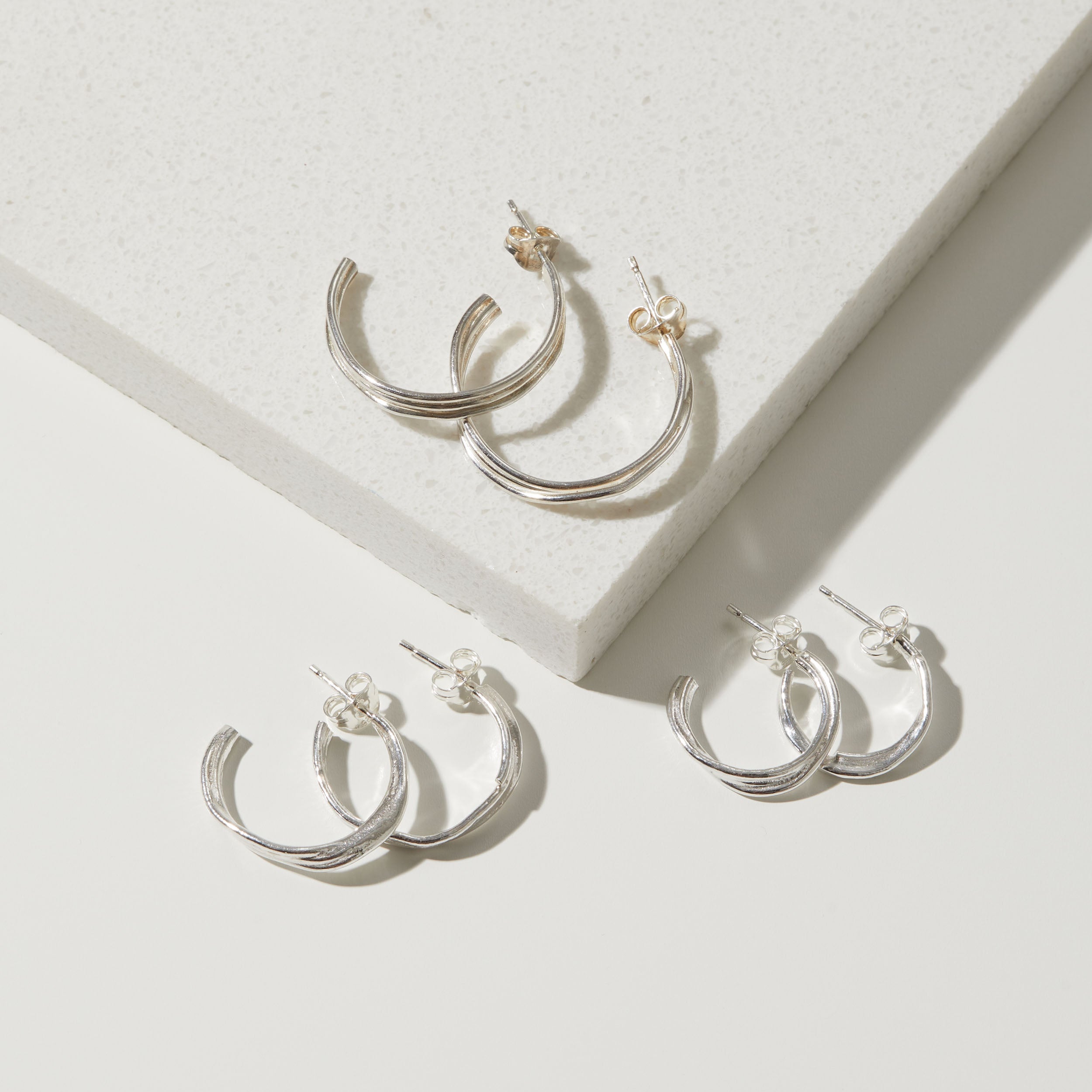 Silver hoop earrings on a light gray surface