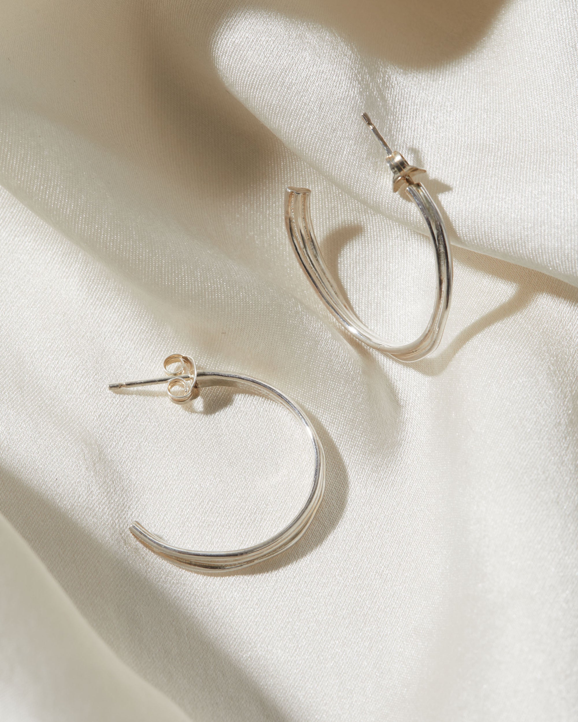 Silver hoop earrings on a light fabric background