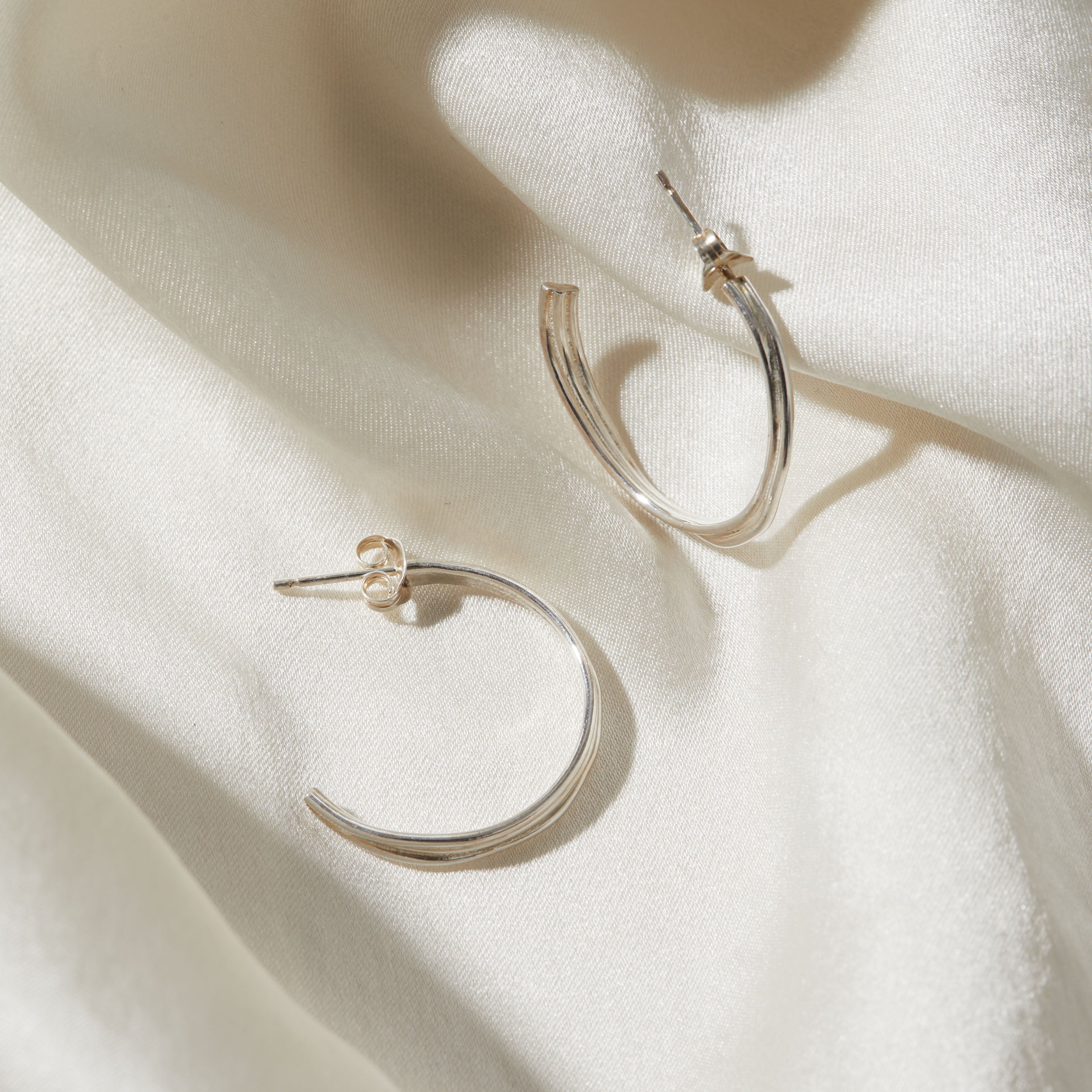 Silver hoop earrings on a light fabric background