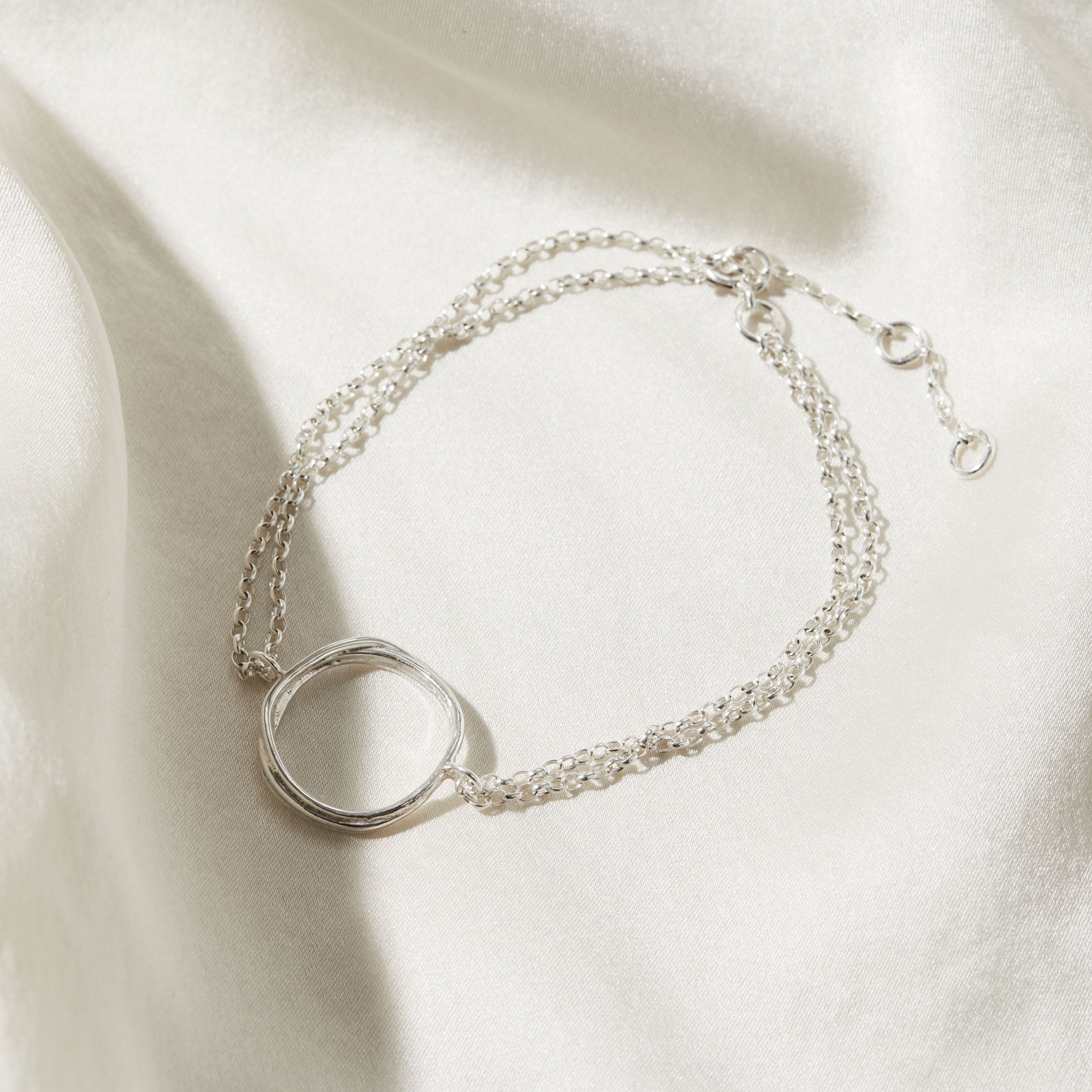 Silver bracelet with a circular design on a light background