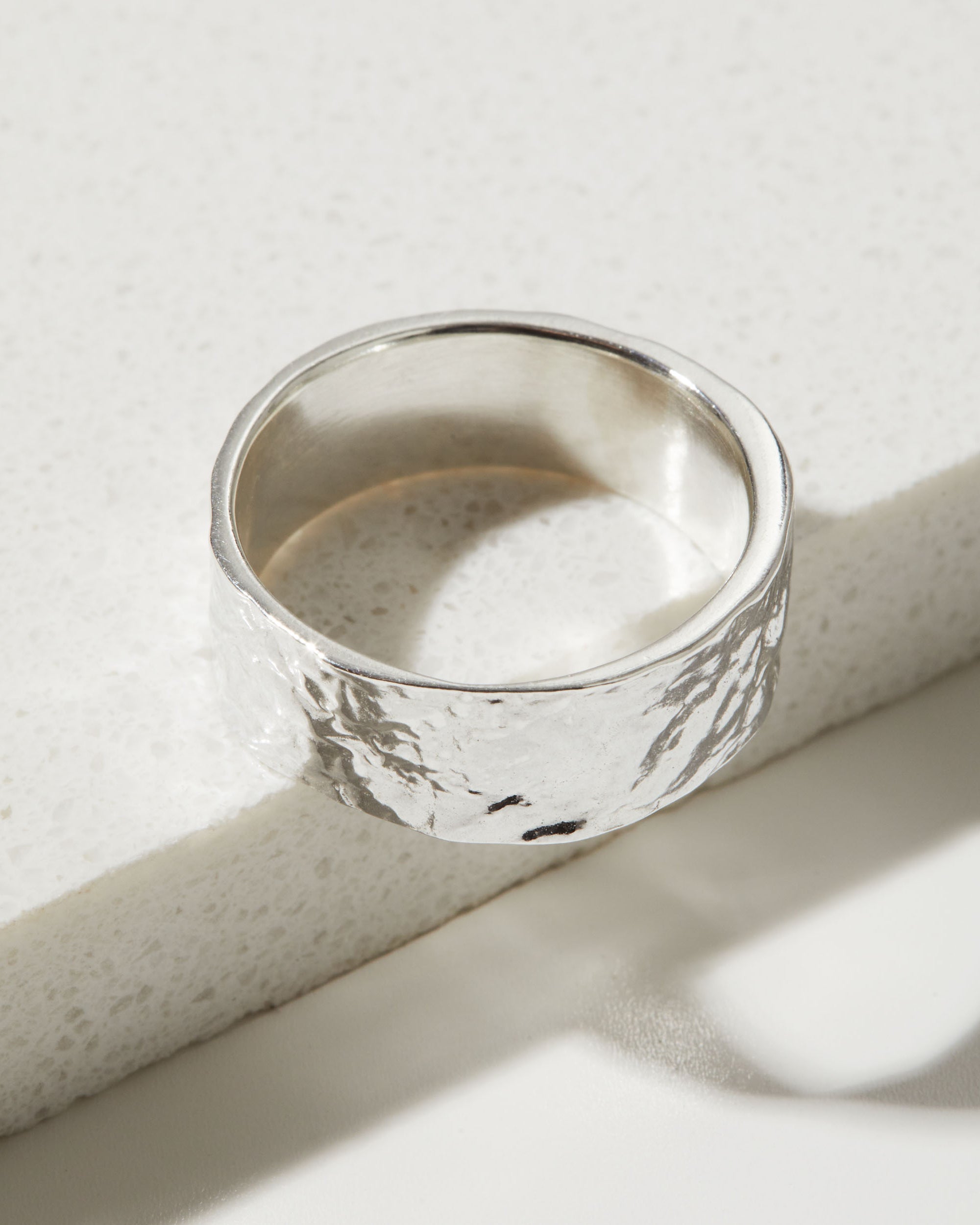 Silver ring with a bark textured surface on a light background