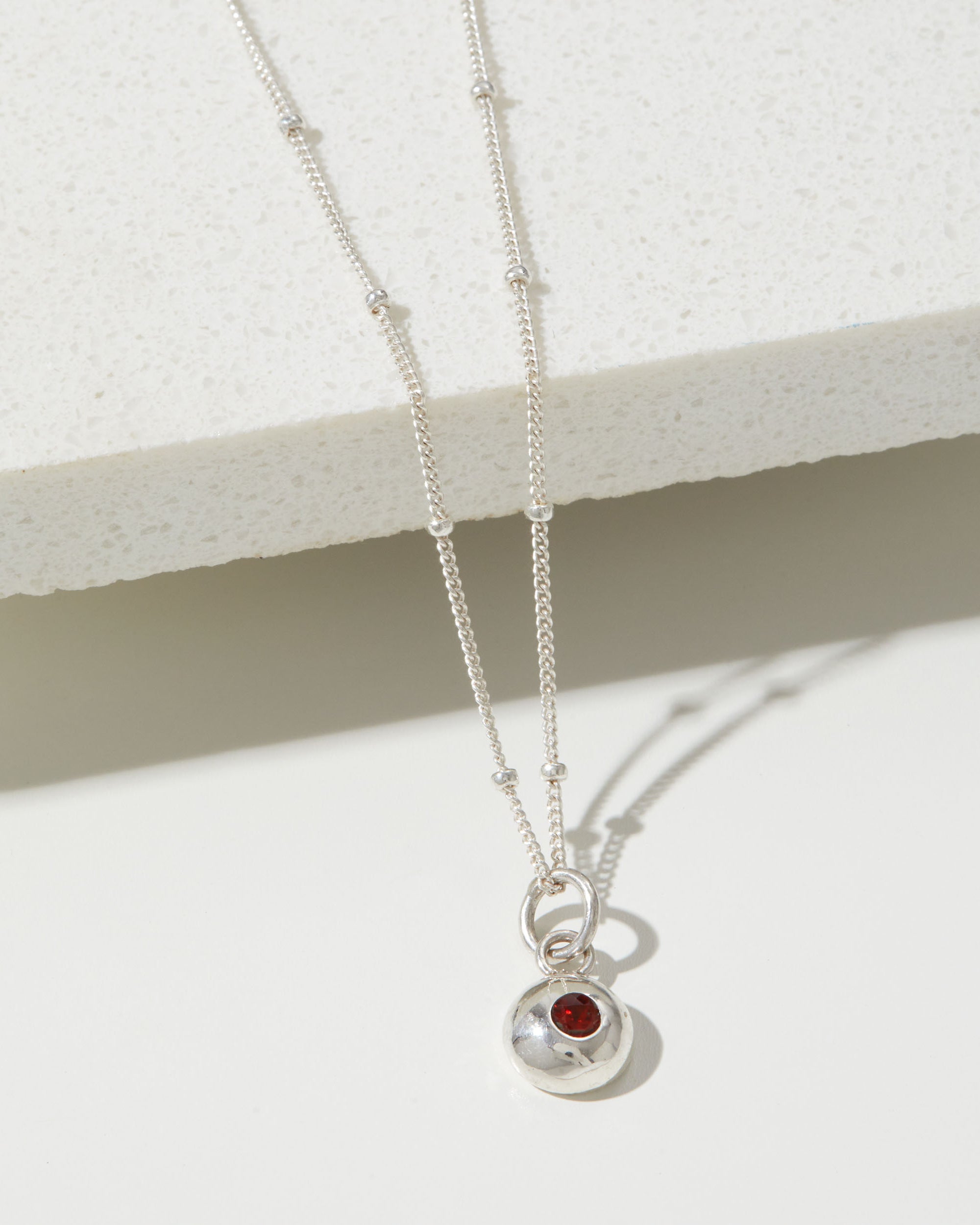 Silver birthstone pendant on a pebble chain.