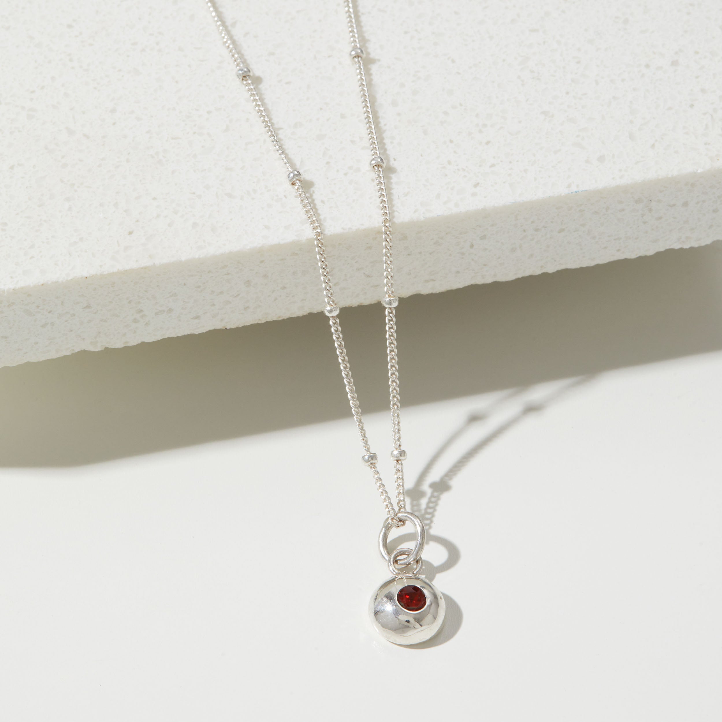 Silver birthstone pendant on a pebble chain.
