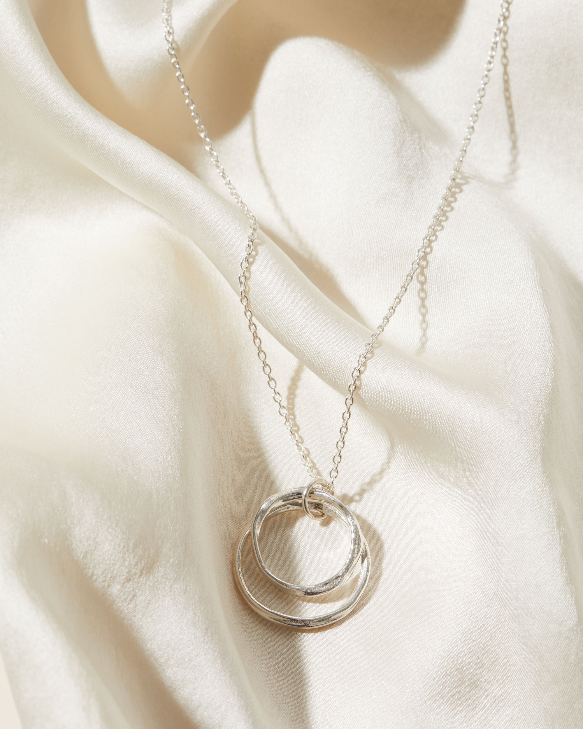 Silver necklace with a pendant on a beige fabric background