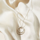 Silver necklace with a pendant on a beige fabric background