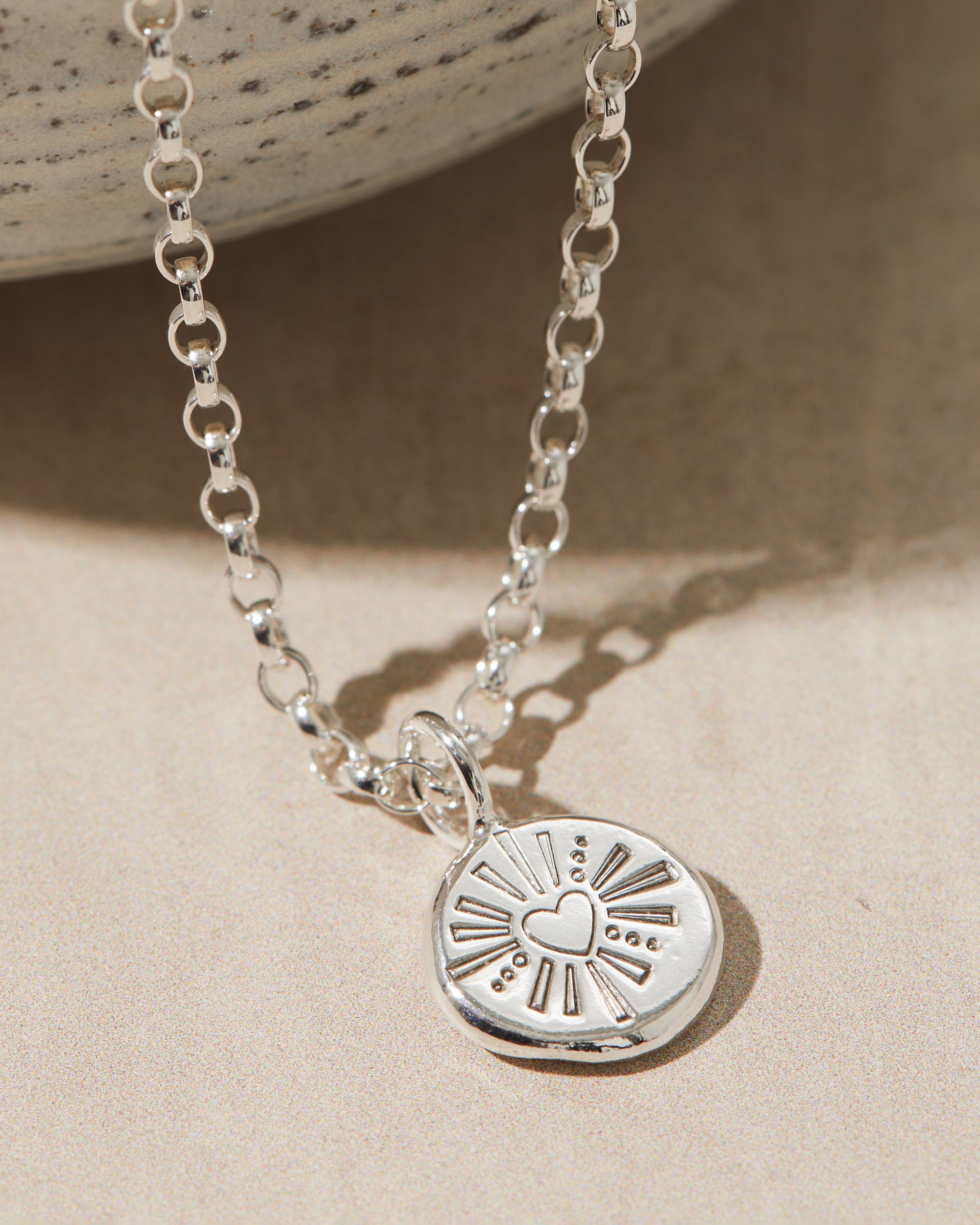 Silver pebble necklace stamped with a heart design.