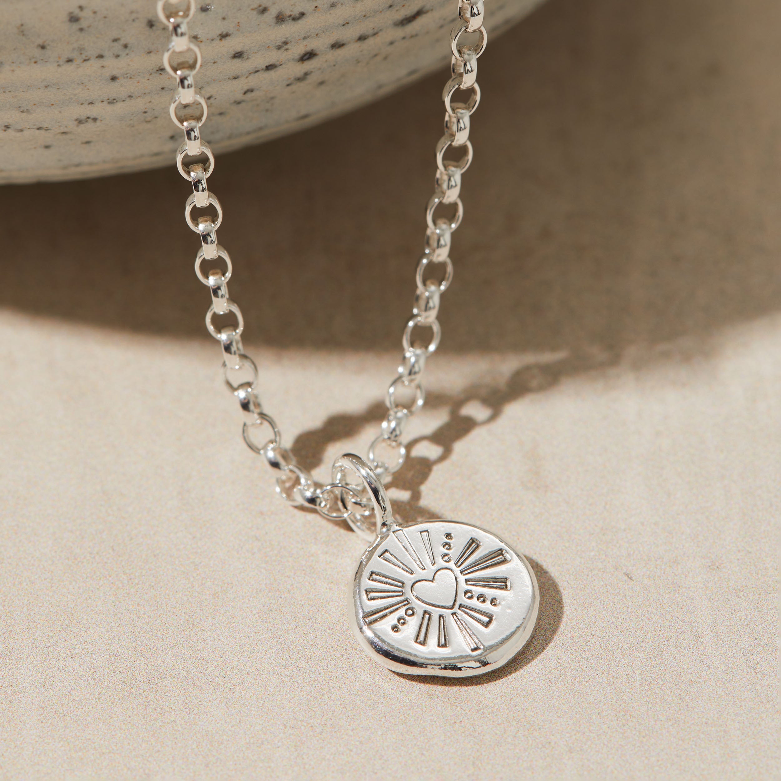 Silver pebble necklace stamped with a heart design.