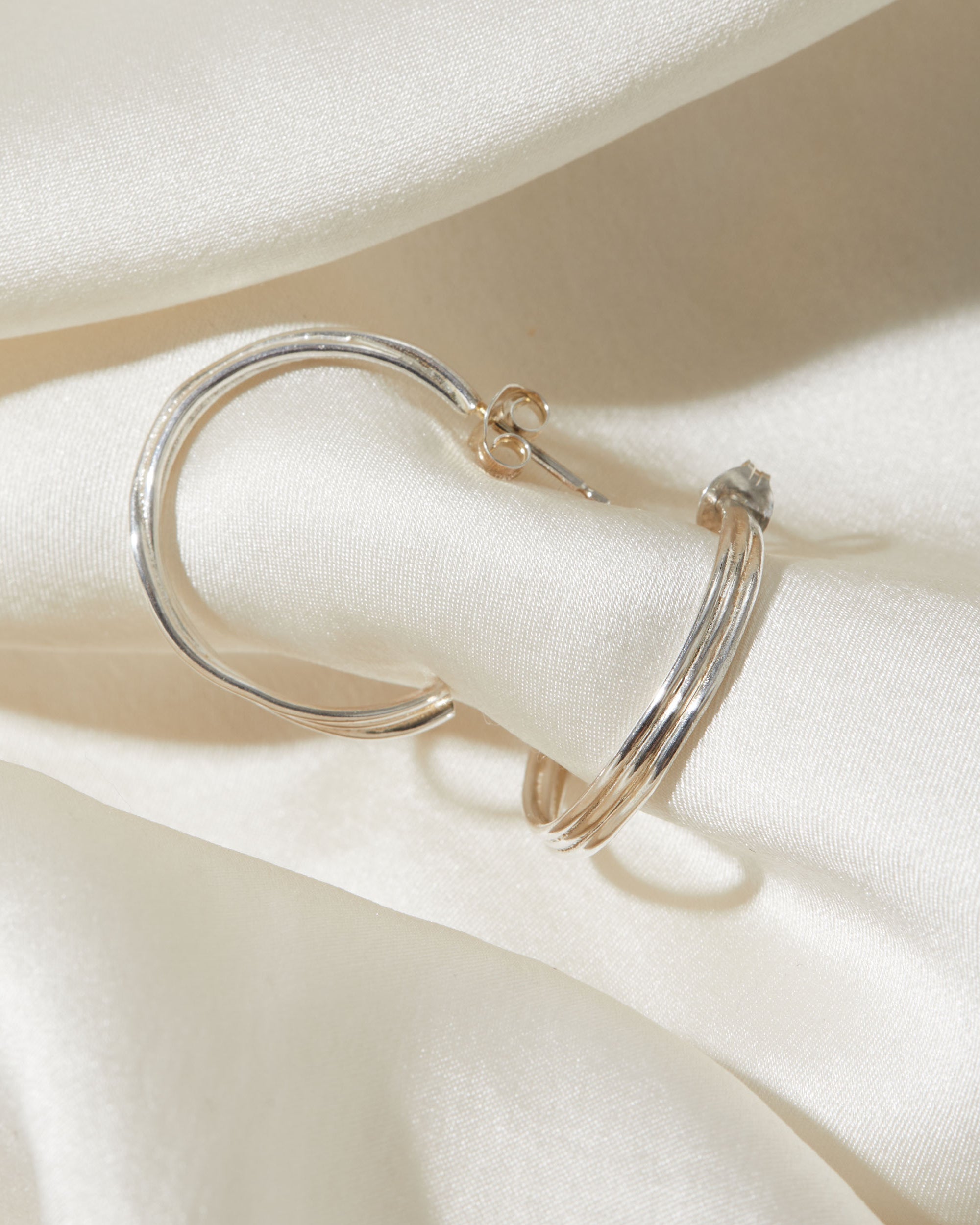 Silver hoop earrings on a white fabric background