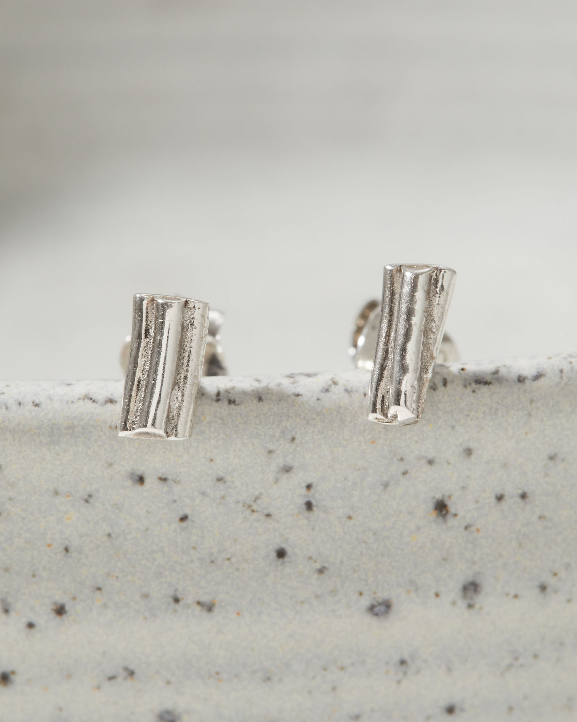 Pair of silver earrings on a textured surface