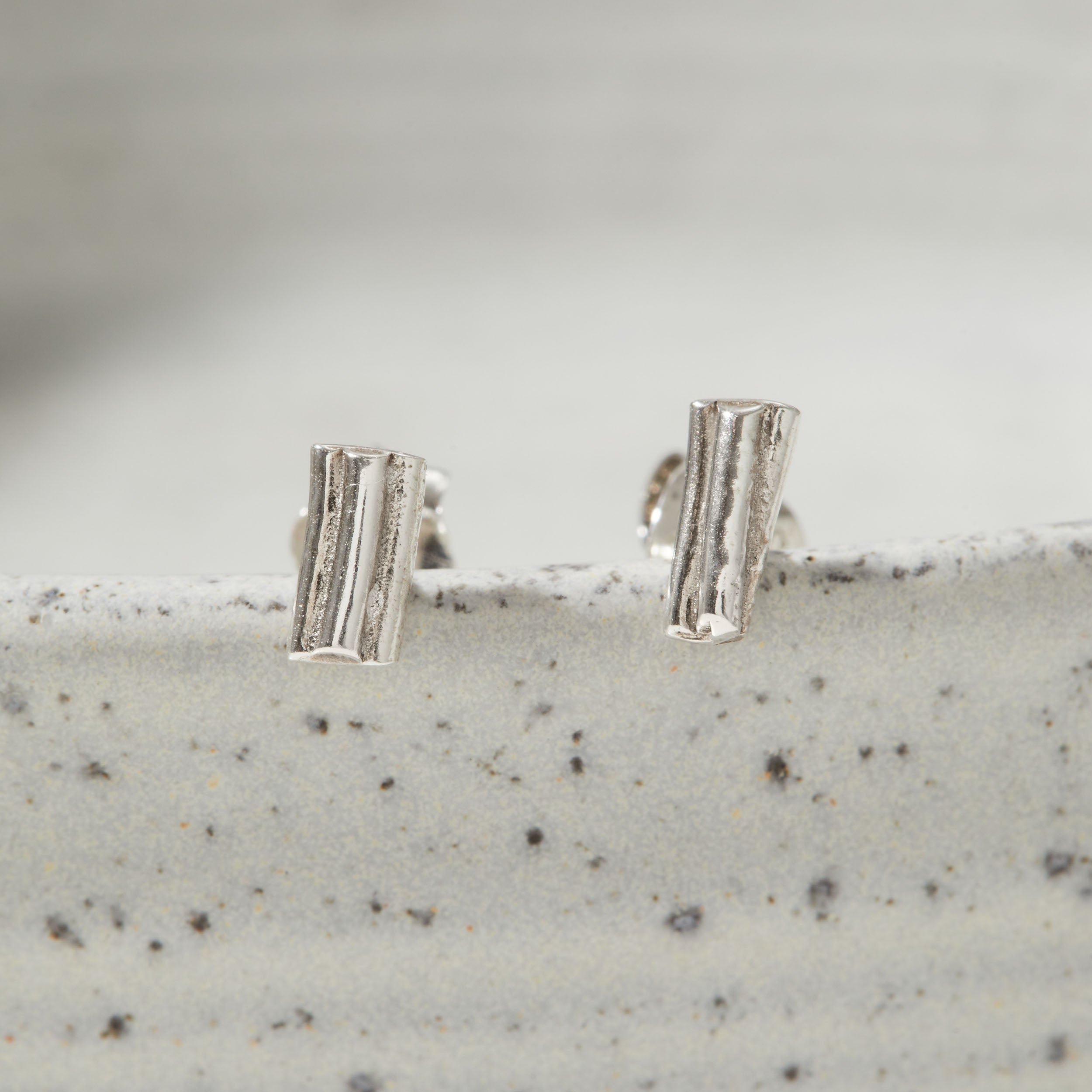 Pair of silver earrings on a textured surface