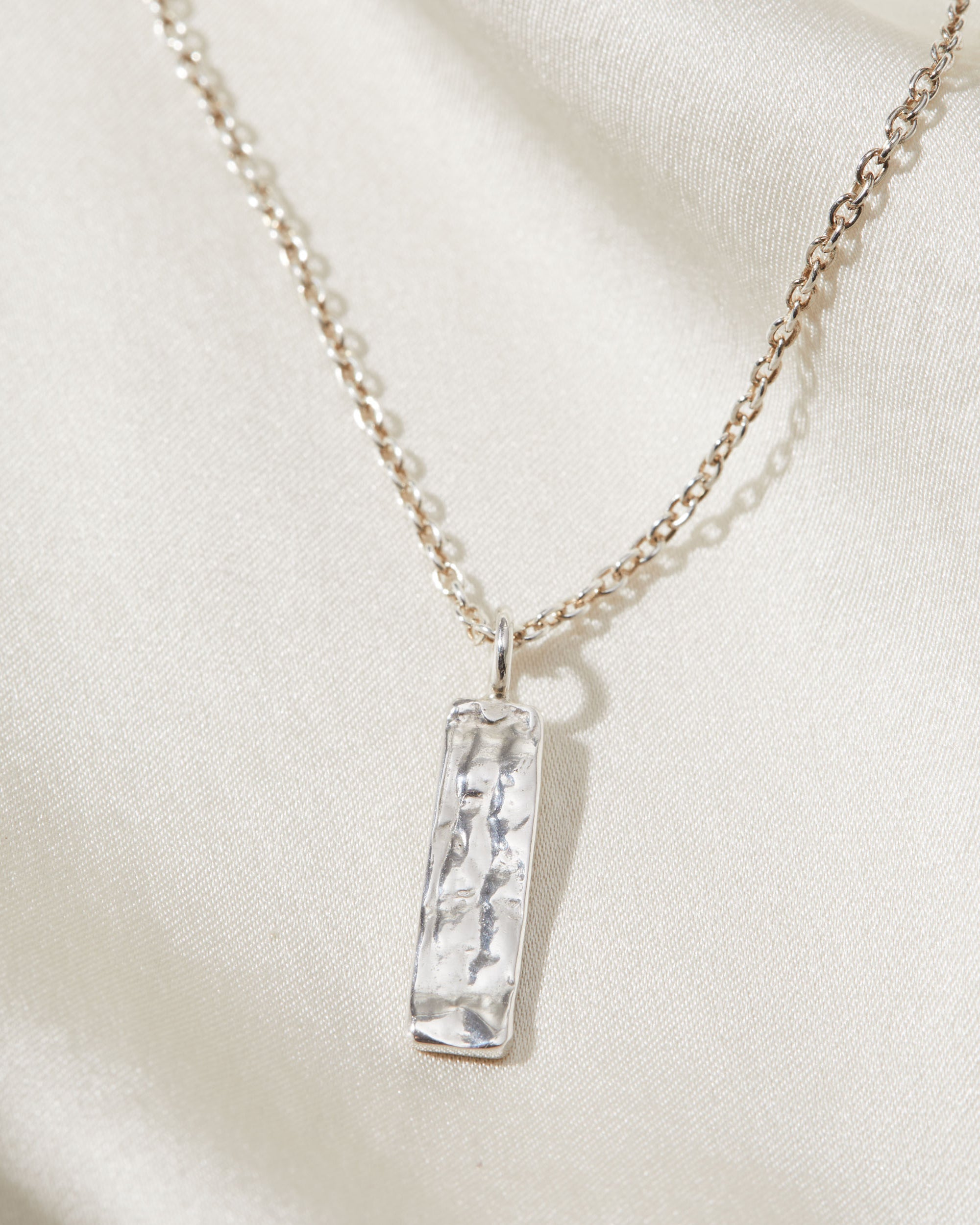 Necklace with a silver pendant on a light beige background
