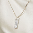 Necklace with a silver pendant on a light beige background