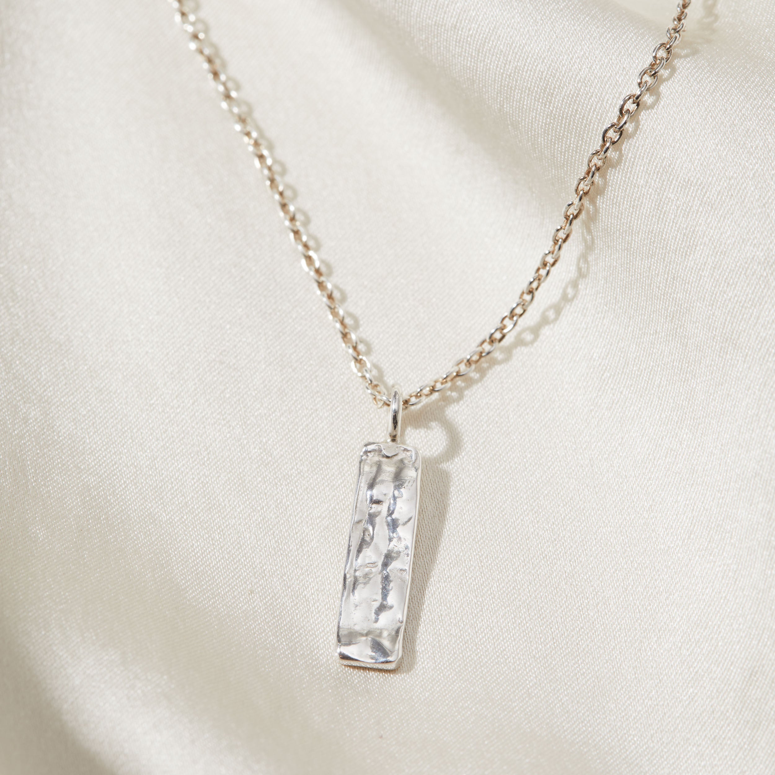 Necklace with a silver pendant on a light beige background