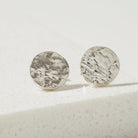 Pair of silver bark textured round earrings on a light background