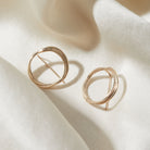 Gold hoop earrings on a beige fabric background