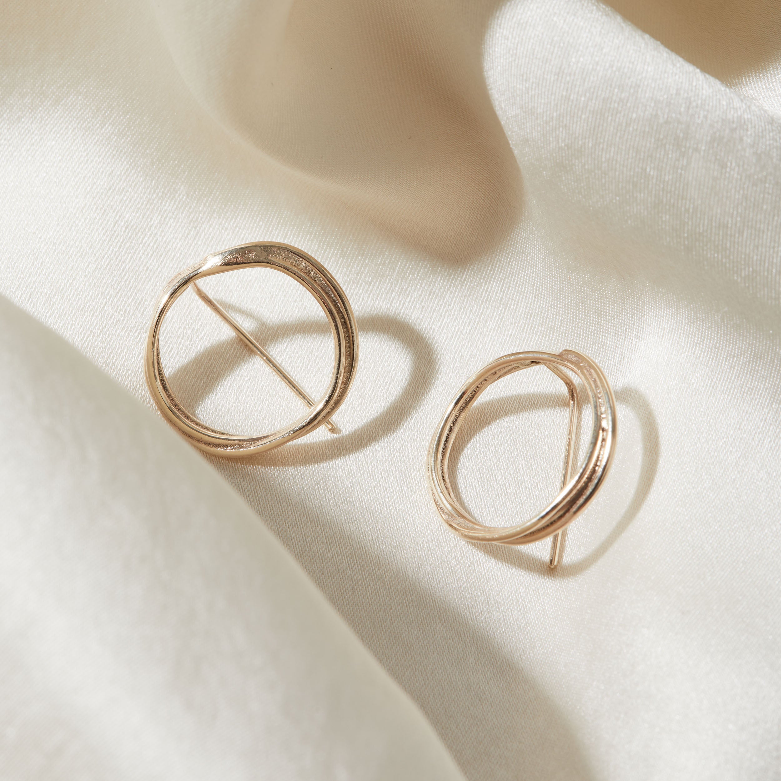 Gold hoop earrings on a beige fabric background