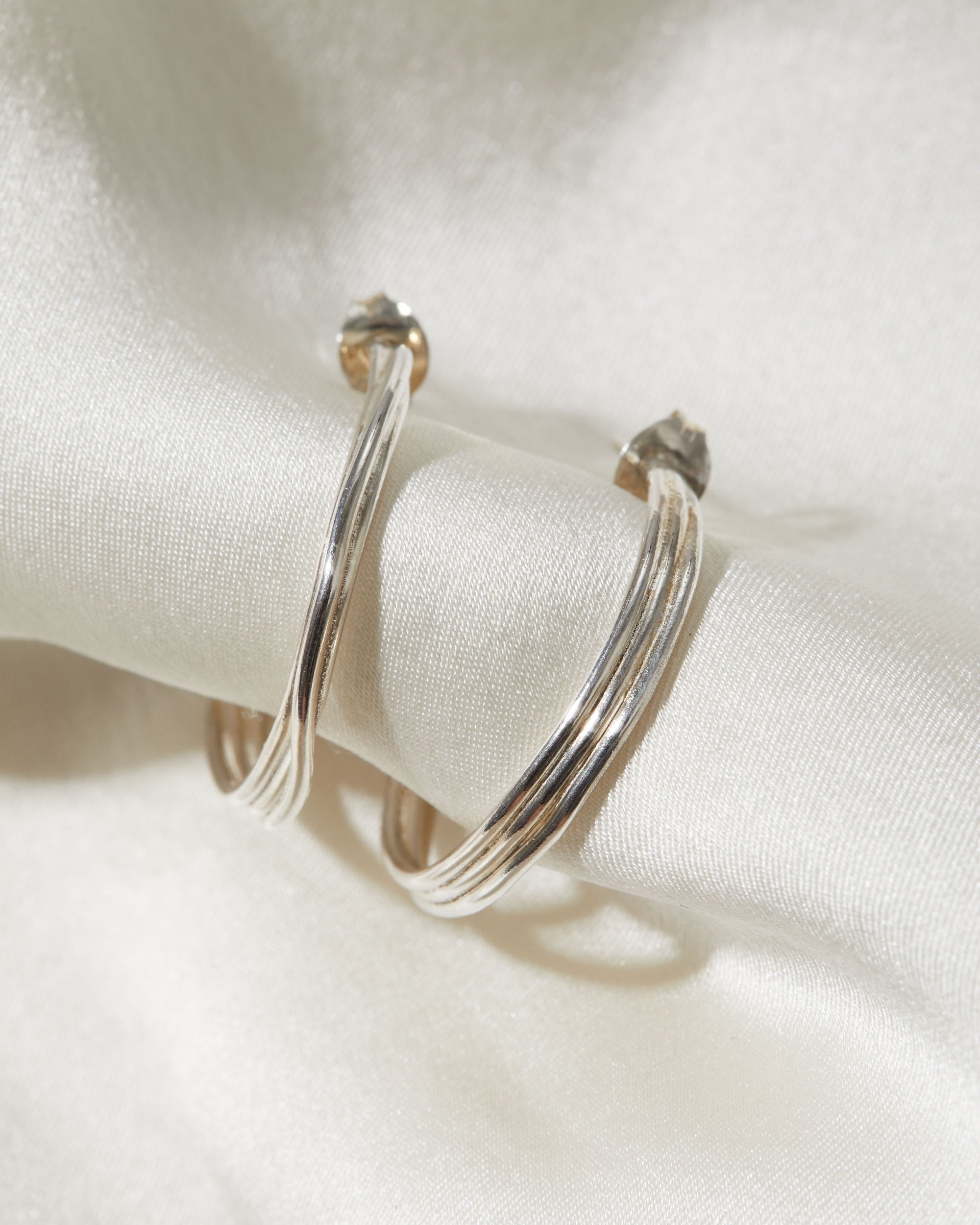 Silver hoop earrings on a white fabric background