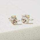 Pair of round earrings with tree textured design on a light background