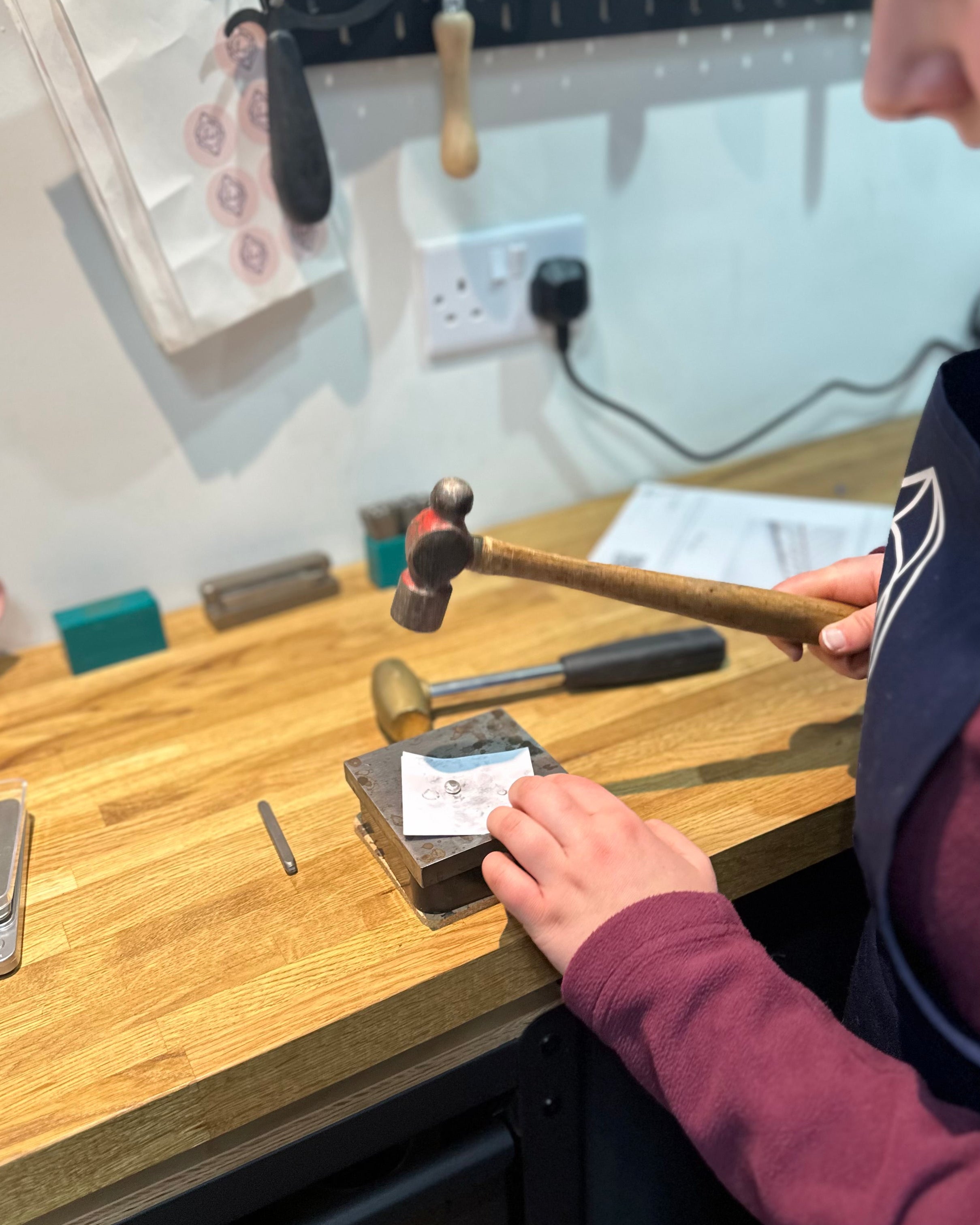 Person working with tools on a wooden workbench in a workshop setting.