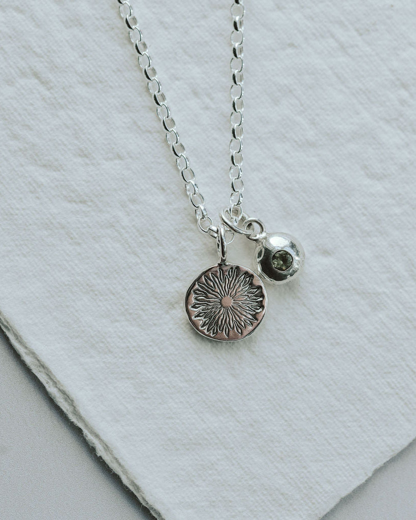 Silver necklace with two pendants on a light gray surface