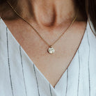 Necklace with a bark textured pendant worn by a person in a white shirt with black stripes.