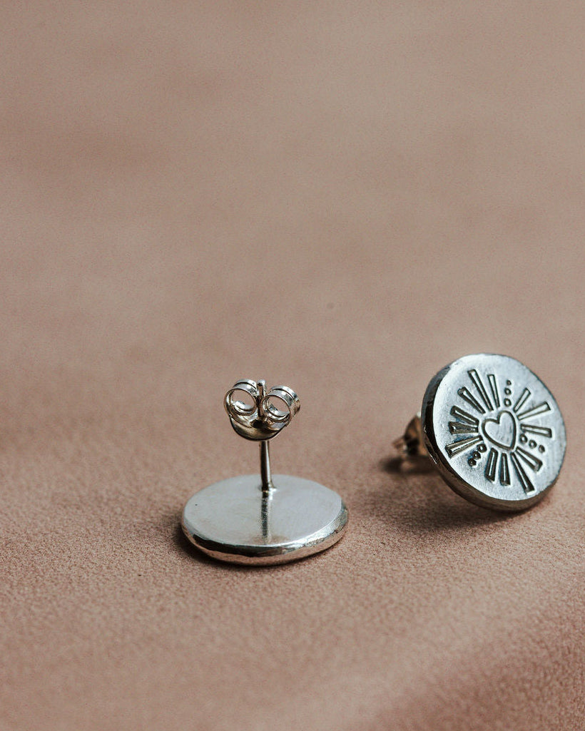 Silver darling heart earrings on a brown surface