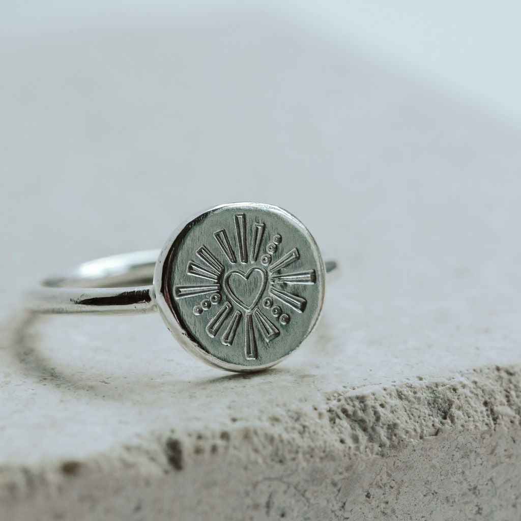 Signet ring with a heart design on a marble tile.